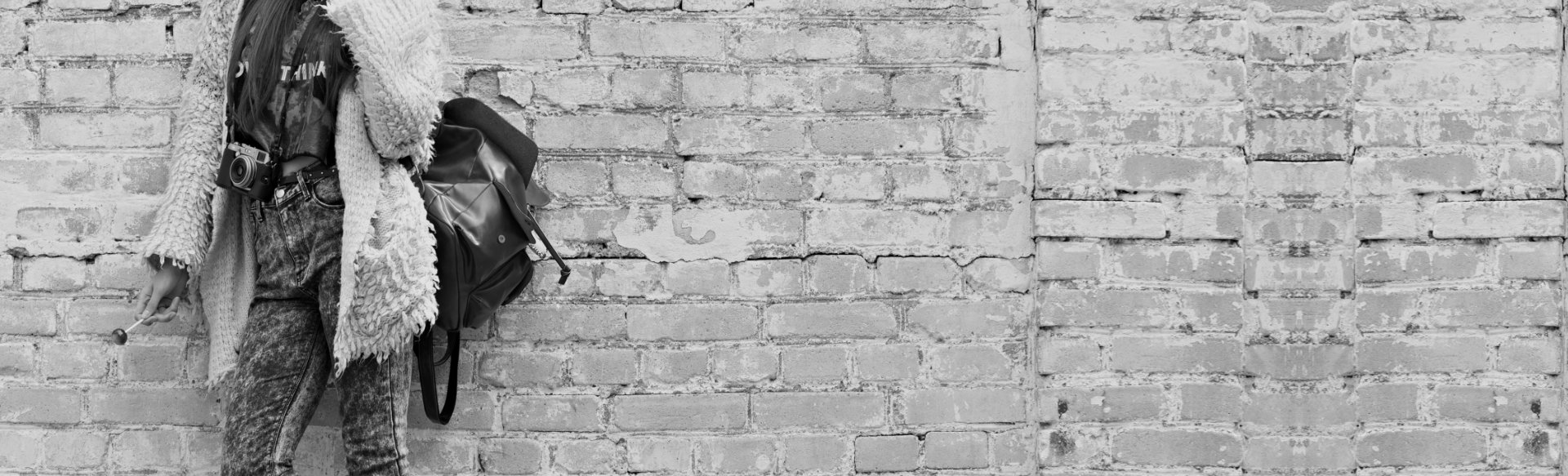 woman leaning on a wall holding a lollipop